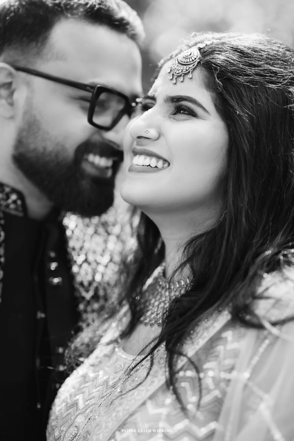 A joyful black-and-white portrait of the couple smiling together